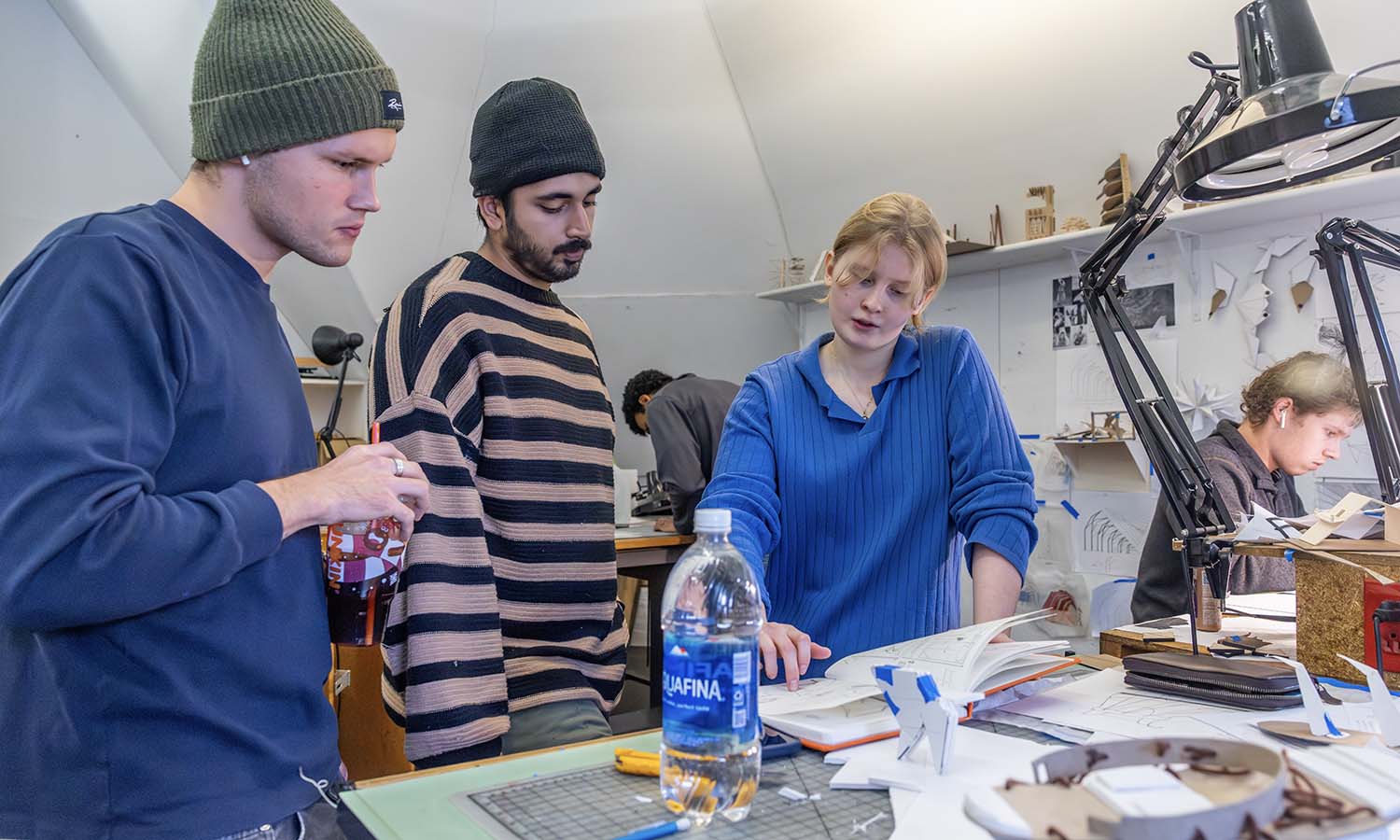 Students stand at studio table