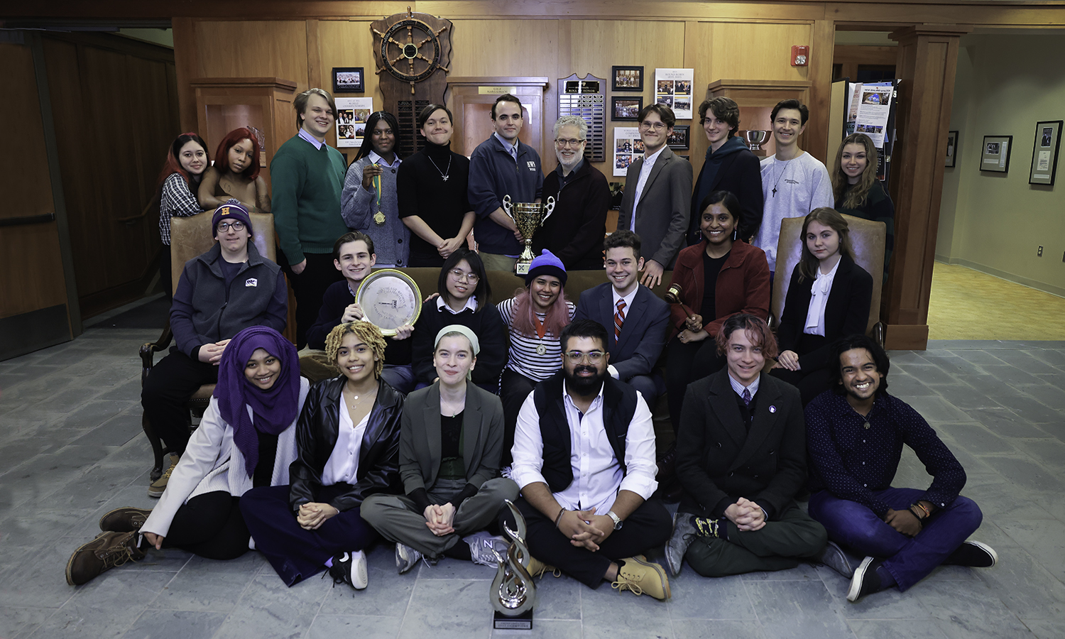 debate team pose for group photo with trophy case
