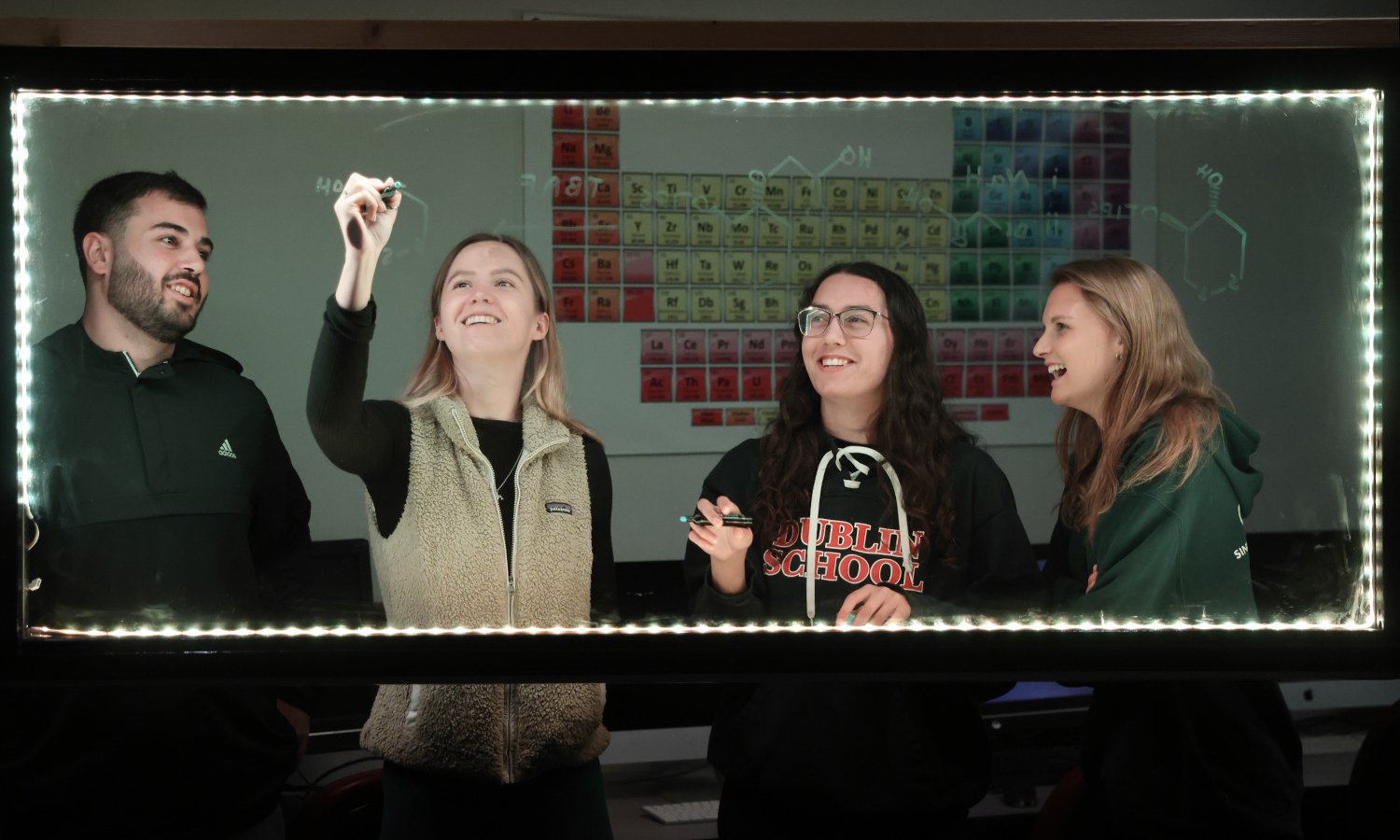 Jonah Silverman ’23, Madison Stewart ’23, Rielly Harrison ’23 and Haley Sax ’23 map out chemical structures on a lightboard in the lab of Professor of Chemistry Justin Miller.