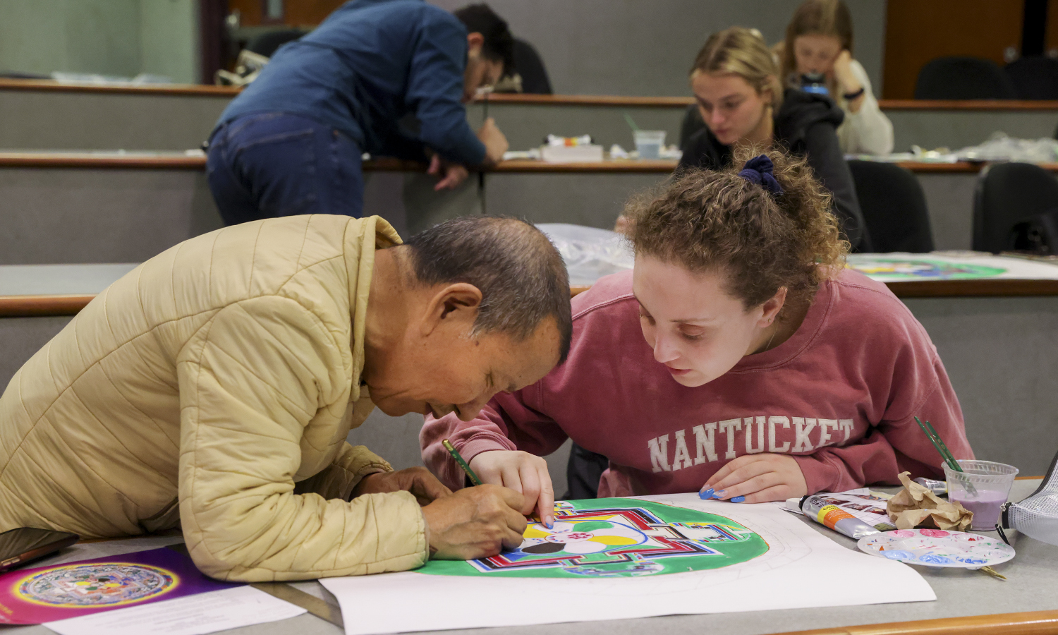The Venerable Tenzin Yignyen, an instructor of Asian Studies and a monk in the Dalai Lama’s personal monastery, works with Jamie Fine ’24 on her assignment during “Tibetan Mandala Painting” class.