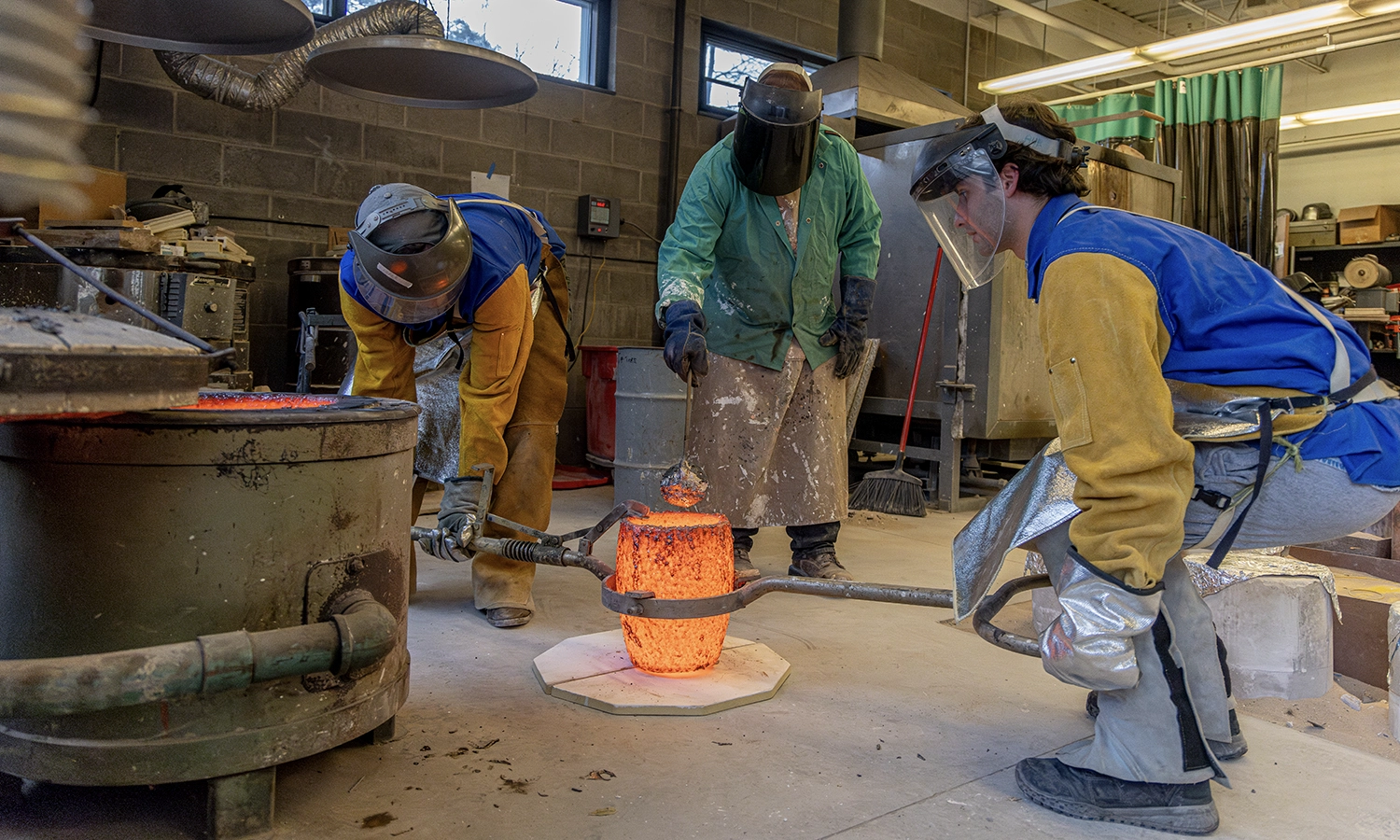 Professor of Art and Architecture Ted Aub assists students in pouring bronze during “Sculpture Workshop.”