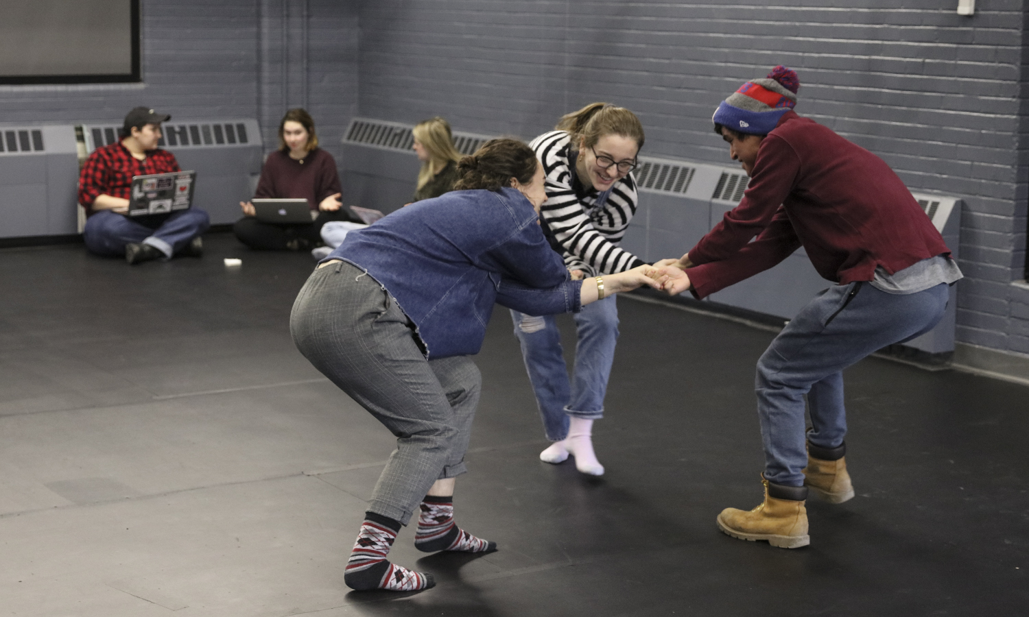 Three students join hands during a theatre class